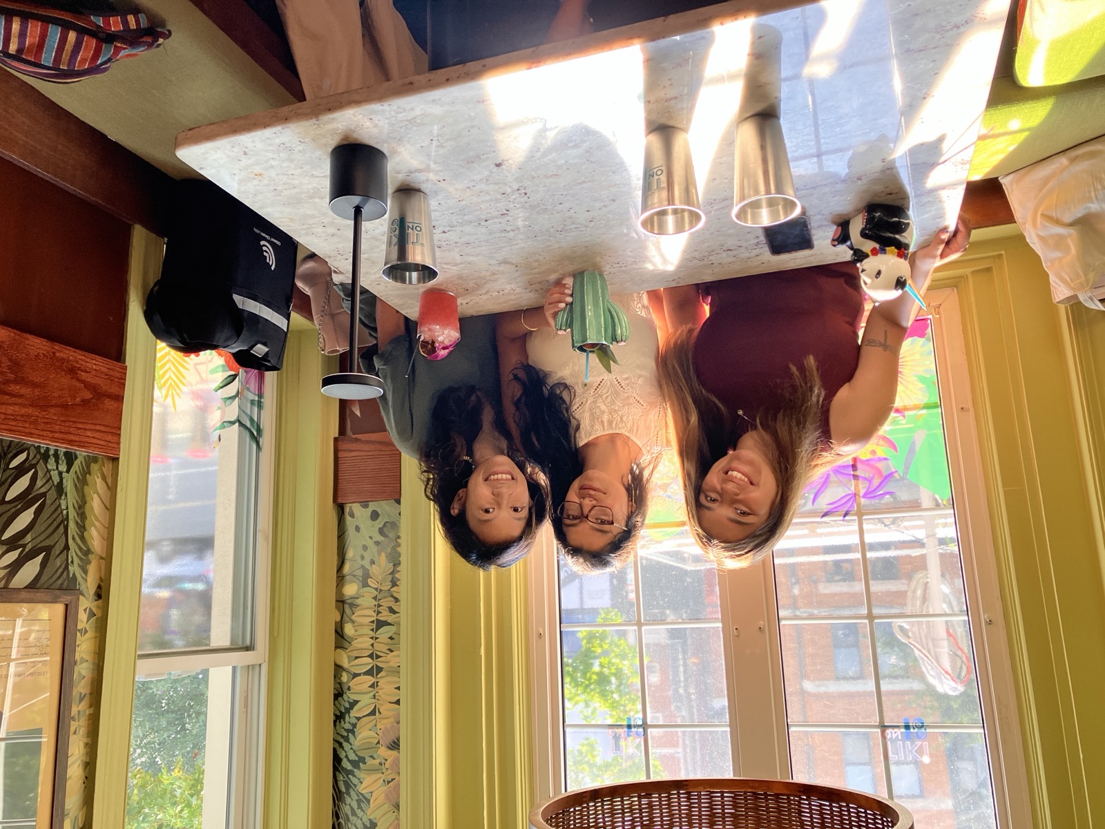 Three PGM volunteers sharing drinks at a sunny caf&eacute; table