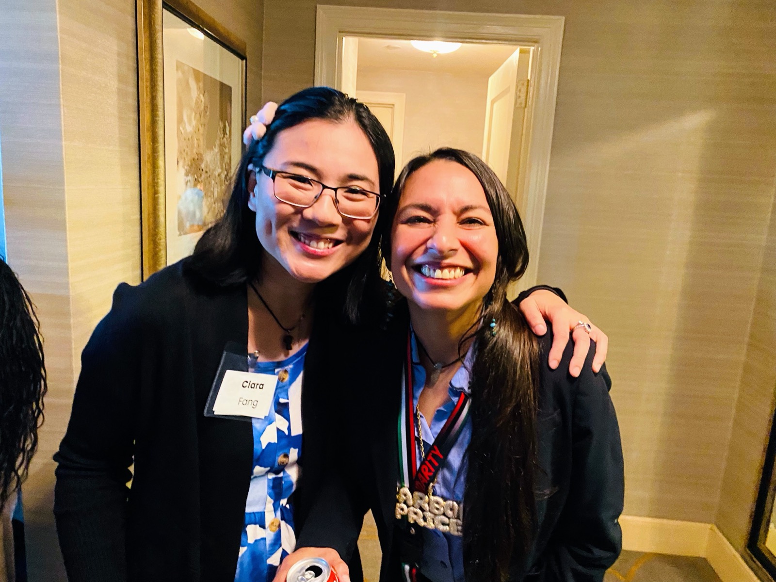 Two PGM volunteers smiling arm in arm at a team gathering