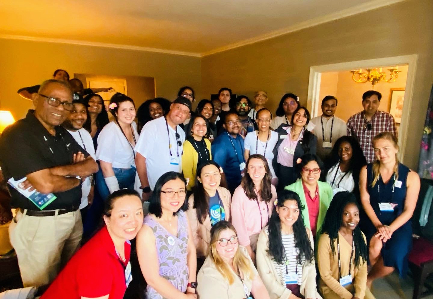 A big smiling group of PGM Action Team members gathered in a living room at the 2023 PGM Gathering