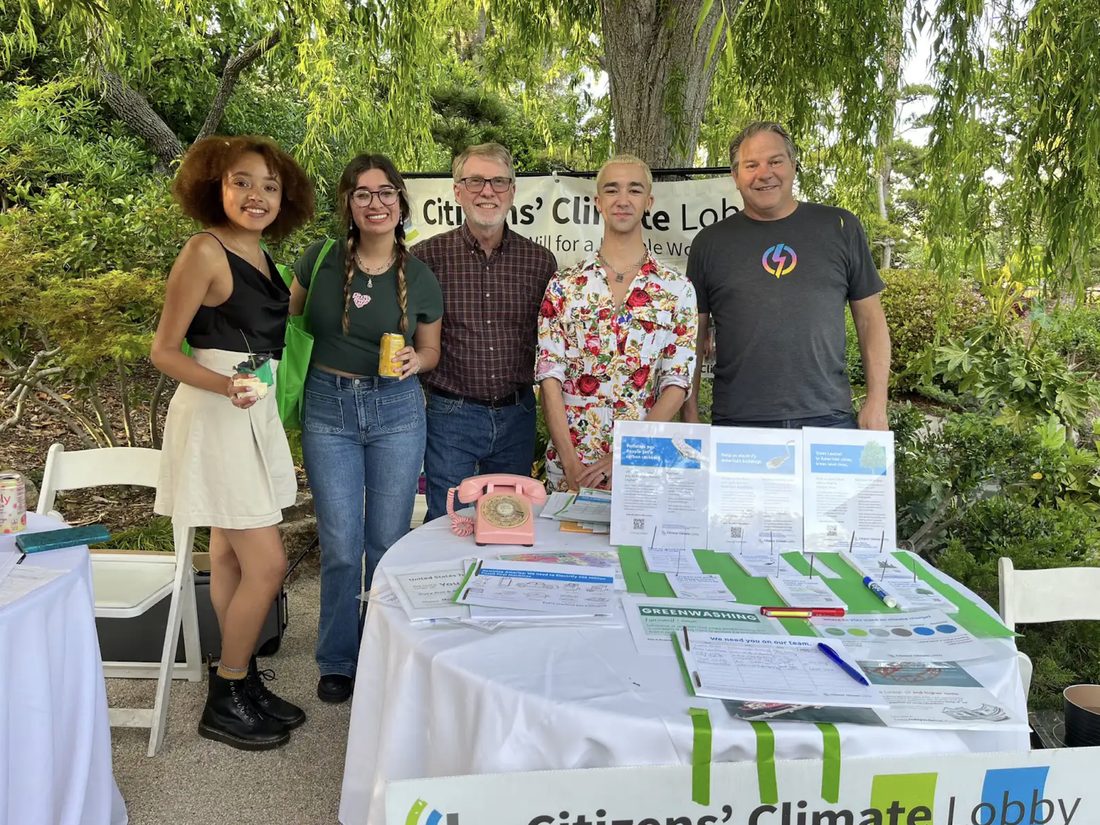 Five volunteers behind a CCL outreach table at an outdoor event
