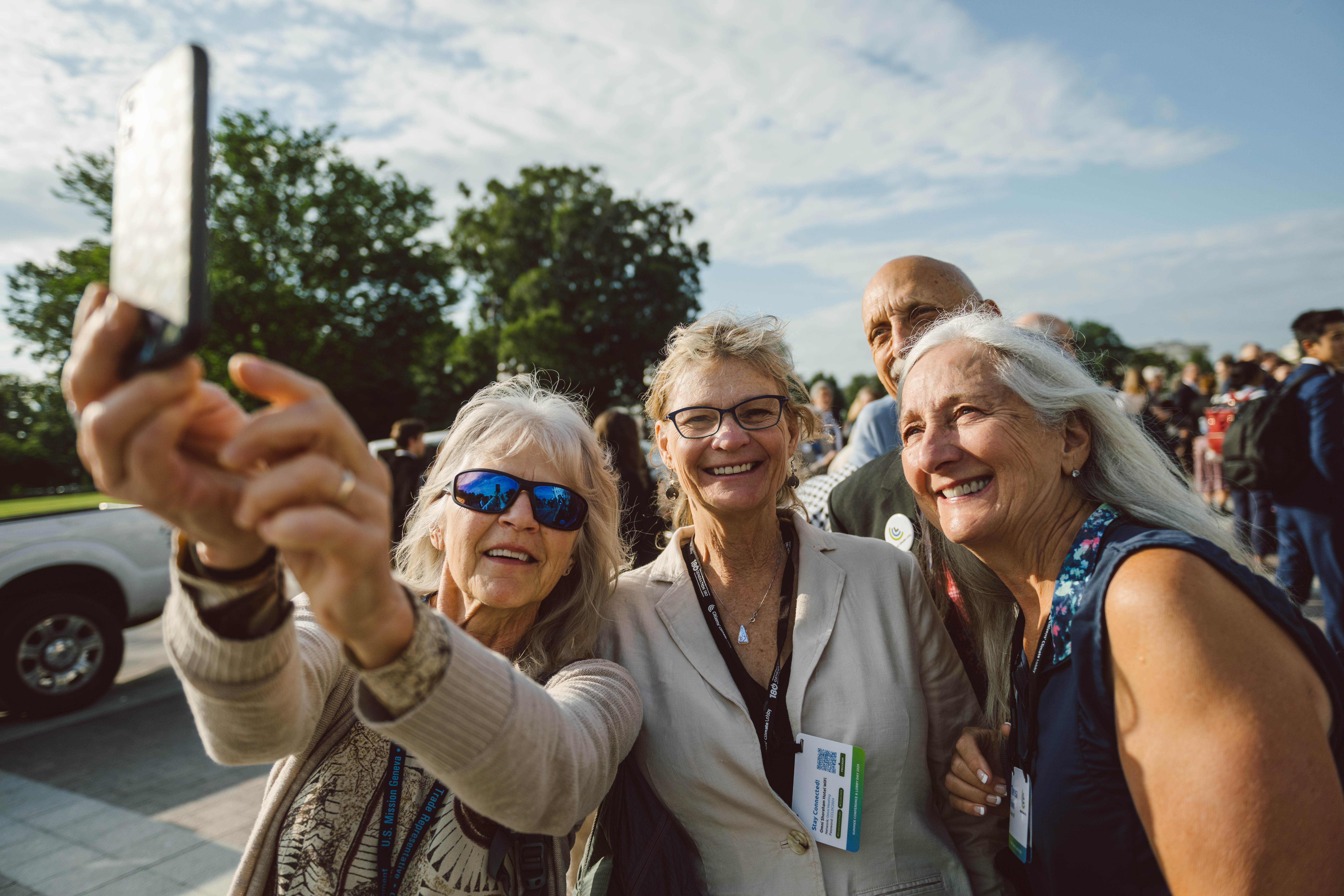 Three CCL volunteers in conference lanyards taking a selfie together outdoors