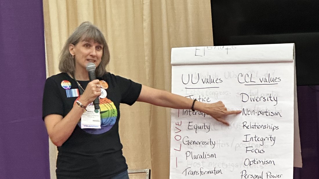 A CCL volunteer presenting to a community group beside a flip chart comparing shared values