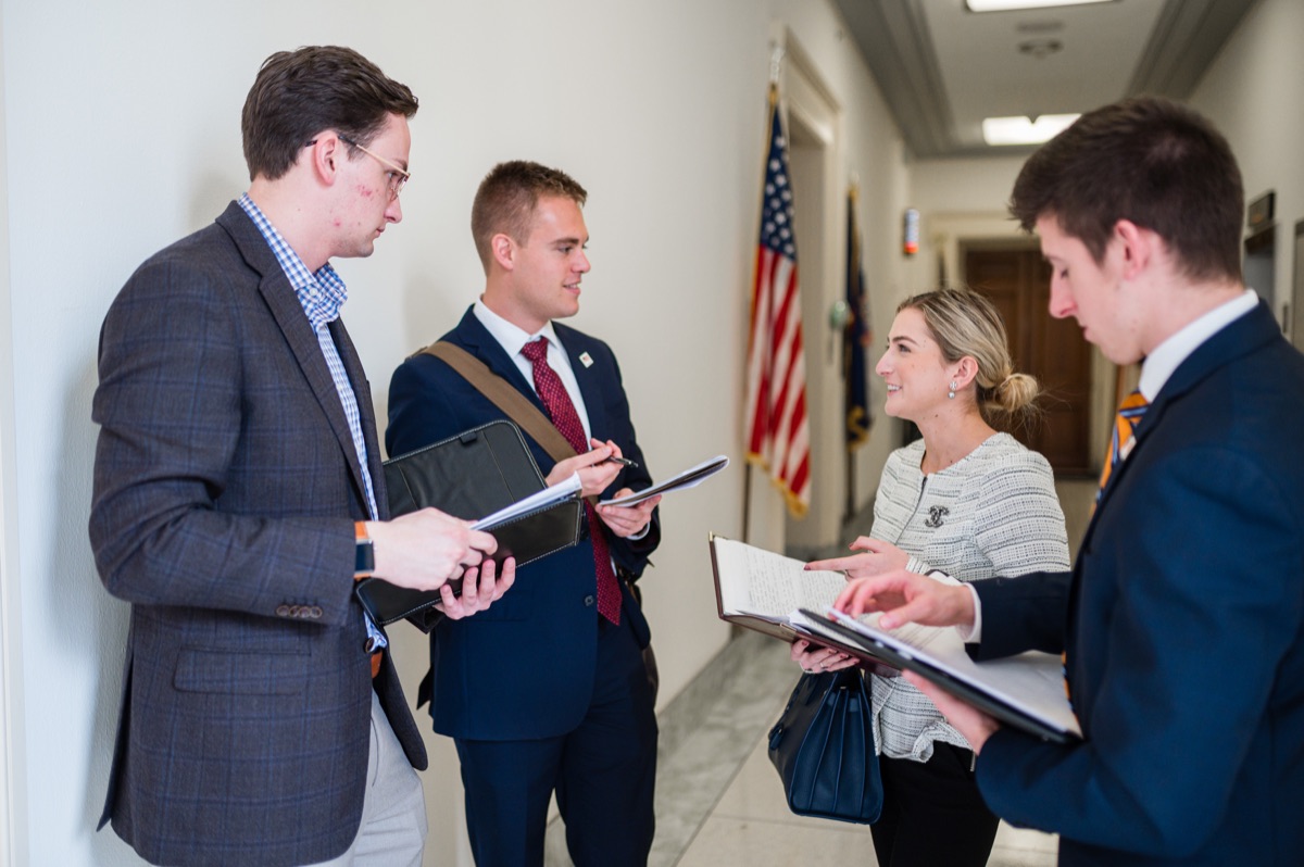 Four volunteers compare notes and binders in a House office building hallway
